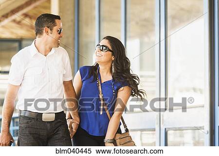 Stock Photography - Hispanic couple holding hands in city. Fotosearch