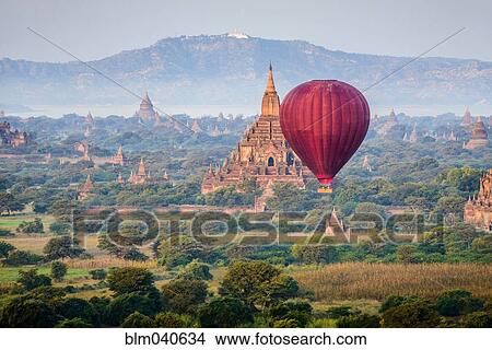 Picture - Hot air balloon flying over towers. Fotosearch