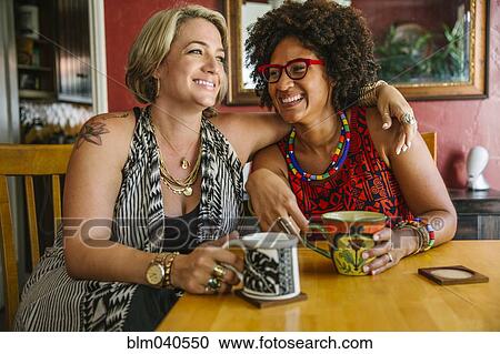 Stock Image - Hugging women drinking coffee. Fotosearch