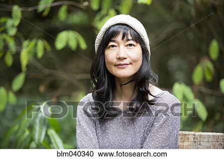 Stock Image - Japanese woman sitting in garden. Fotosearch