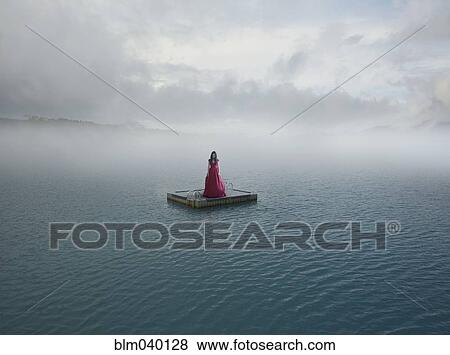 Stock Photo - Middle Eastern woman floating on dock in remote lake. Fotosearch