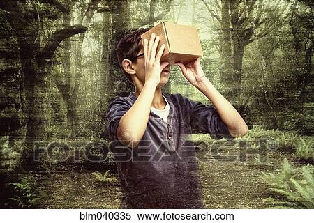 Stock Photography - Mixed race boy peering in box in forest. Fotosearch
