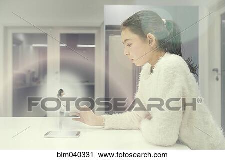 Stock Image - Mixed race girl examining hologram projection. Fotosearch