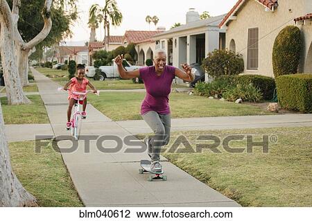 Mother and daughter riding skateboard and bicycle on sidewalk View Large Photo Image Stock Image - Mother and daughter riding skateboard and bicycle on sidewalk. Fotosearch