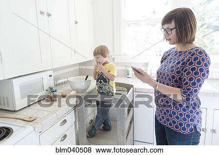 Stock Photo - Mother and son standing in kitchen. Fotosearch