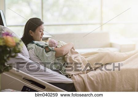 Mother cradling newborn baby in hospital room View Large Photo Image Stock Photo - Mother cradling newborn baby in hospital room. Fotosearch