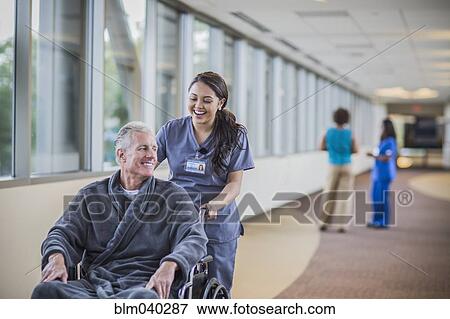 Stock Photo - Nurse pushing patient in wheelchair. Fotosearch