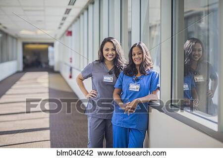 Stock Image - Nurses smiling in hospital hallway. Fotosearch