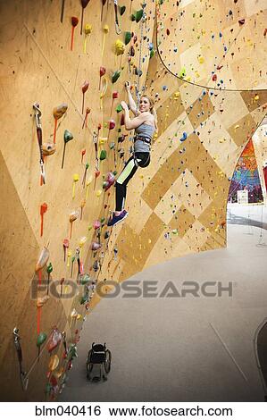 Stock Photograph - Paraplegic woman rock climbing in gym. Fotosearch
