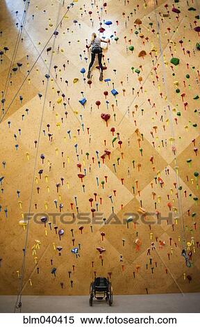 Stock Photography - Paraplegic woman rock climbing in gym. Fotosearch