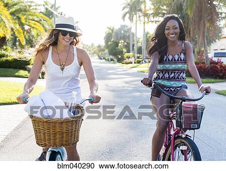 Stock Image - Smiling women riding bicycles. Fotosearch
