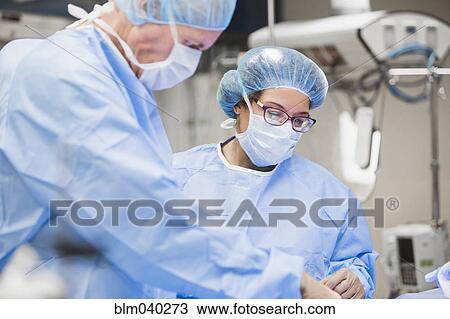 Stock Image - Surgeons working in operating room. Fotosearch