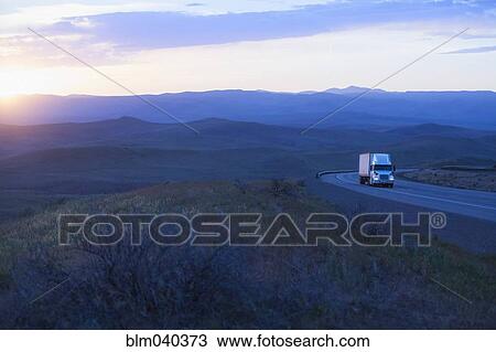 Stock Image - Truck driving on remote highway. Fotosearch