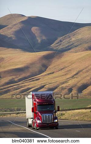Stock Image - Truck driving on remote highway. Fotosearch