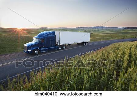 Stock Image - Truck driving on remote highway. Fotosearch