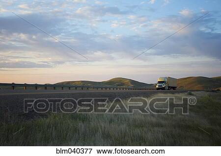 Stock Photo - Truck driving on remote highway. Fotosearch