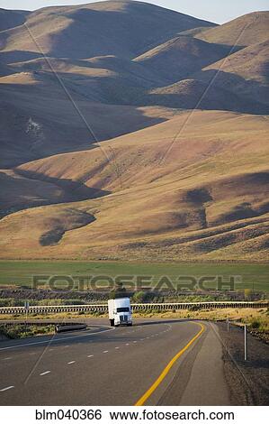Stock Photograph - Truck driving on remote highway. Fotosearch