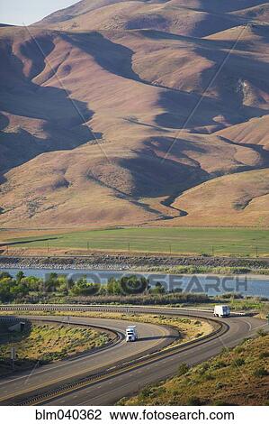 Stock Image - Trucks driving on remote highway. Fotosearch