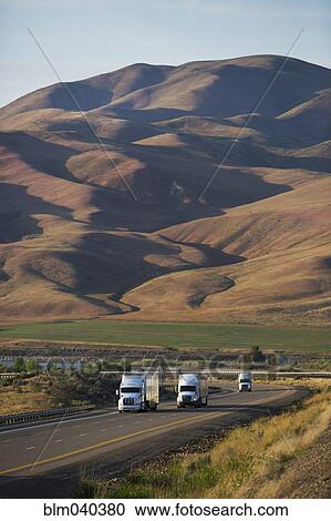 Trucks driving on remote highway View Large Photo Image Stock Image - Trucks driving on remote highway. Fotosearch