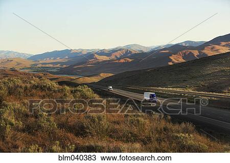 Trucks driving on remote highway View Large Photo Image Stock Image - Trucks driving on remote highway. Fotosearch