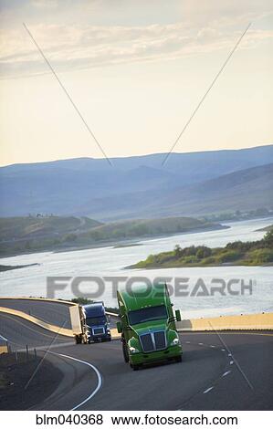 Trucks driving on remote highway View Large Photo Image Stock Photo - Trucks driving on remote highway. Fotosearch