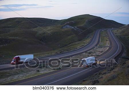 Stock Photograph - Trucks driving on remote highway. Fotosearch