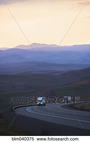 Trucks driving on remote highway View Large Photo Image Stock Photography - Trucks driving on remote highway. Fotosearch