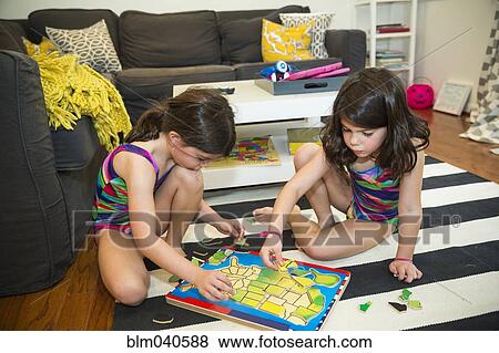 Twin sisters doing puzzle on floor View Large Photo Image Stock Photo - Twin sisters doing puzzle on floor. Fotosearch