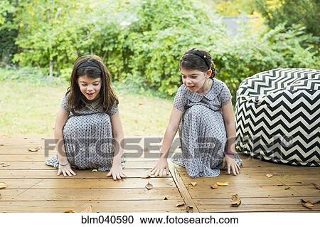 Stock Image - Twin sisters playing on deck. Fotosearch