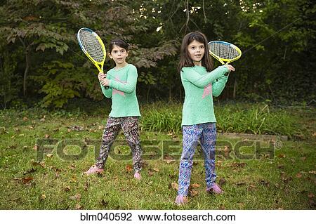 Twin sisters playing tennis in grass View Large Photo Image Stock Image - Twin sisters playing tennis in grass. Fotosearch