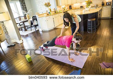 Stock Image - Woman exercising with trainer in home. Fotosearch