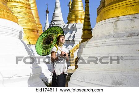 Stock Image - Asian woman carrying parasol at temple. Fotosearch