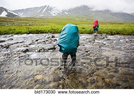 Backpackers crossing remote stream View Large Photo Image Stock Image - Backpackers crossing remote stream. Fotosearch