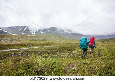 Stock Photo - Backpackers walking on rural path. Fotosearch