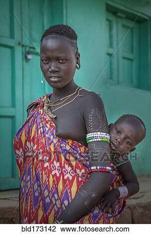 Stock Image - Black woman carrying daughter in sling. Fotosearch
