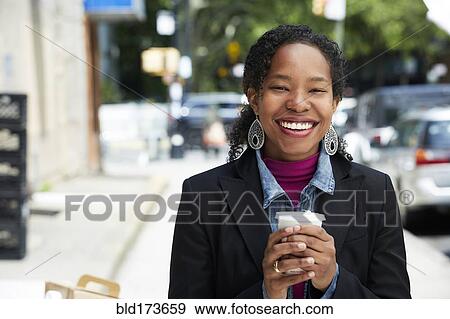Stock Photo - Black woman drinking coffee outdoors. Fotosearch