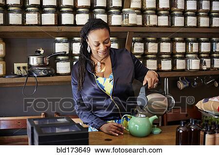 Black woman pouring tea in tea shop View Large Photo Image Stock Photo - Black woman pouring tea in tea shop. Fotosearch