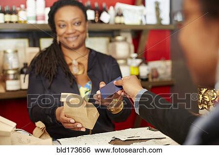 Stock Photograph - Black woman serving customer in tea shop. Fotosearch