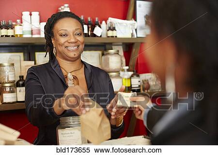 Stock Photography - Black woman serving customer in tea shop. Fotosearch