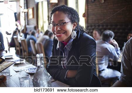 Stock Image - Black woman sitting at restaurant table. Fotosearch