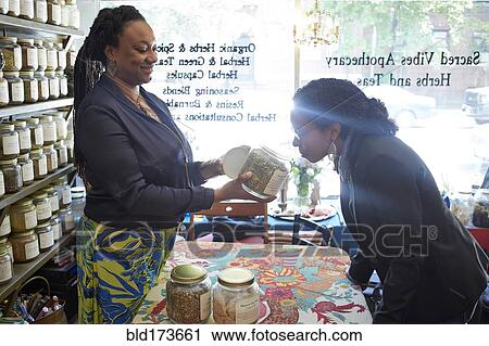 Stock Image - Black woman smelling tea in tea shop. Fotosearch
