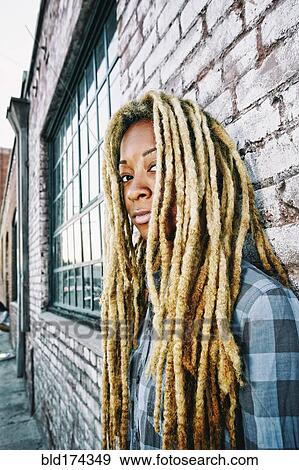 Stock Photo - Black woman with dreadlocks at brick wall. Fotosearch