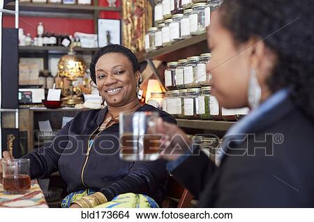 Picture - Black women drinking tea in tea shop. Fotosearch