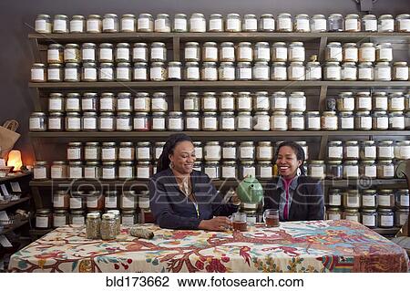 Stock Image - Black women drinking tea in tea shop. Fotosearch
