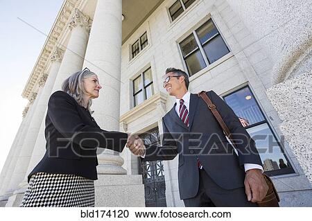 Stock Image - Business people shaking hands courthouse. Fotosearch