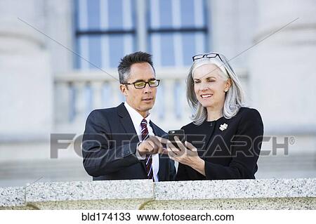 Business people using cell phone outside courthouse View Large Photo Image Stock Image - Business people using cell phone outside courthouse. Fotosearch