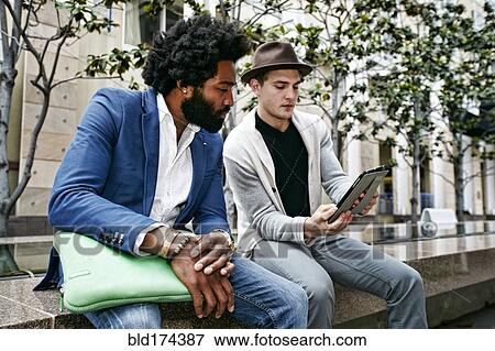 Businessmen using digital tablet outdoors View Large Photo Image Stock Photo - Businessmen using digital tablet outdoors. Fotosearch