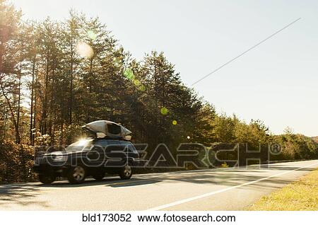 Stock Image - Car driving on rural road. Fotosearch