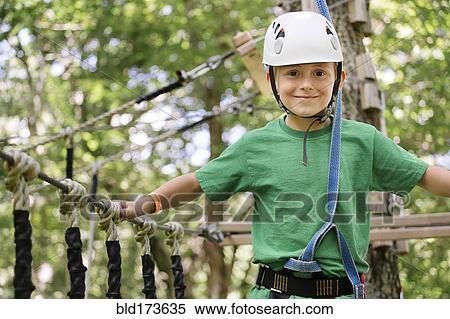 Stock Photography - Caucasian boy balancing on rope bridge. Fotosearch