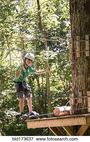 Stock Photo - Caucasian boy balancing on slackline in forest. Fotosearch
